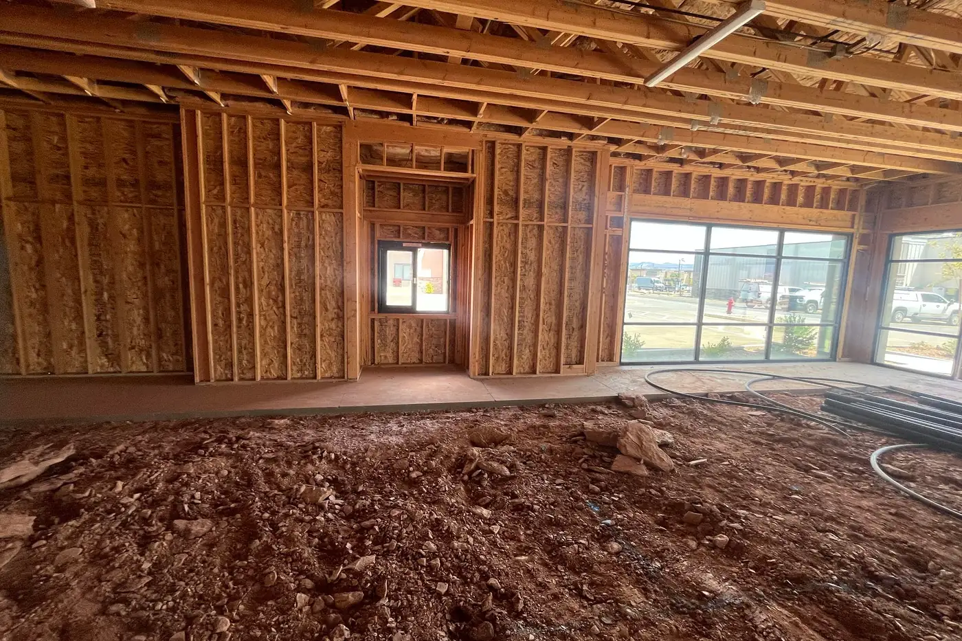 Framed interior walls inside the Agave Animal Hospital building, with a window set into a recessed opening, a strip of poured concrete along the wall base, and storefront glazing letting in daylight at right.